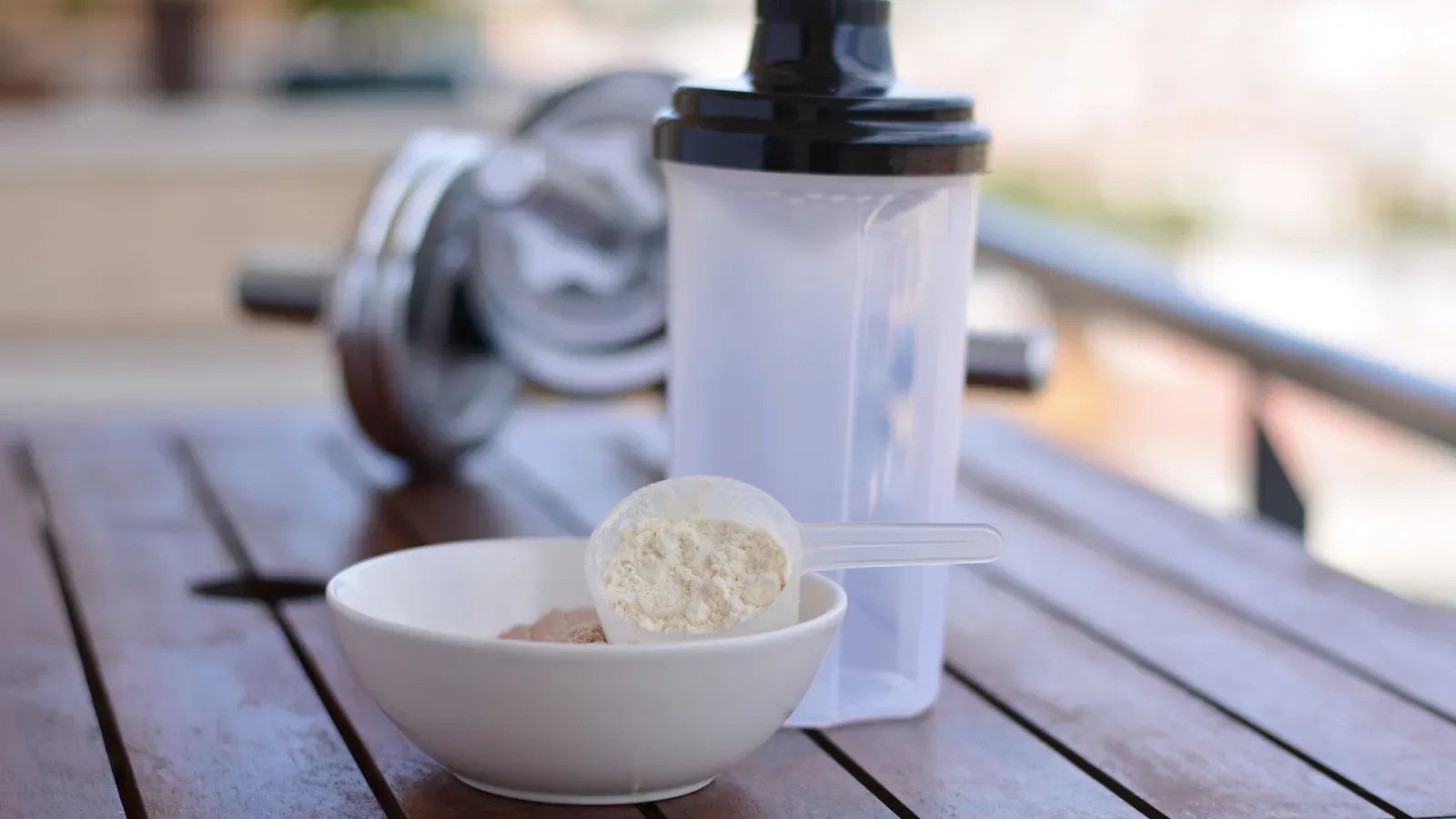 Proteinpulver, skopa och shaker på ett bord